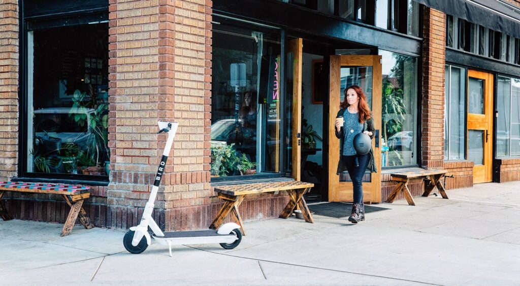 Woman walking out of coffee shop to her parked Bird